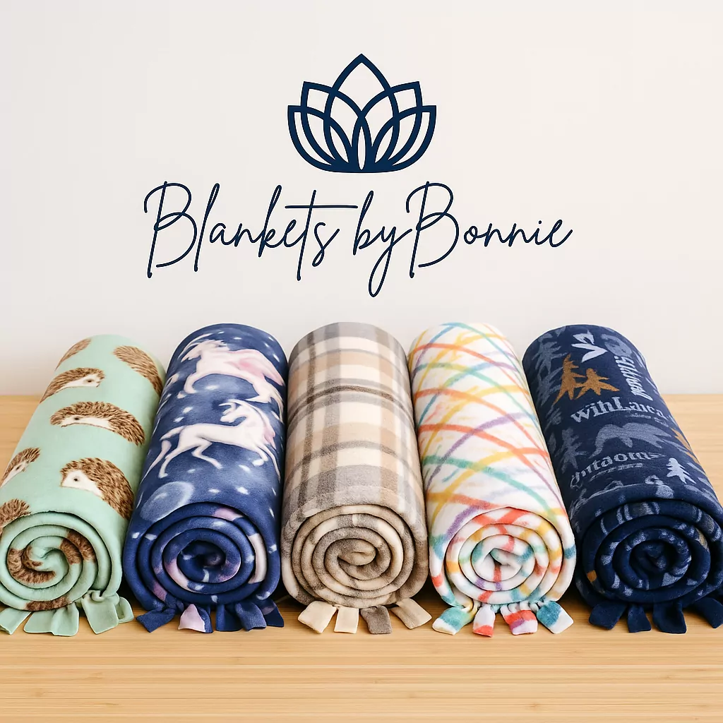 Five rolled fleece tie blankets in hedgehog, unicorn, plaid, rainbow, and forest patterns lined up on a wooden table